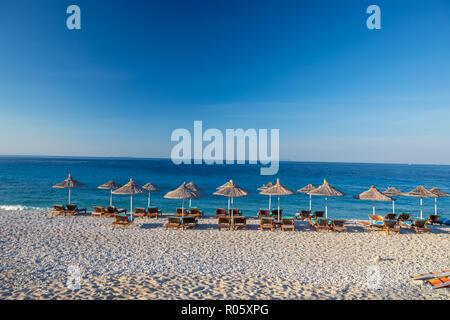 Paradiso sulla spiaggia. Alberi tropicali e lettini sulla spiaggia. L'Albania Foto Stock