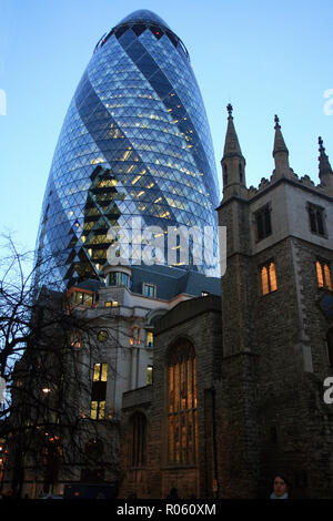 La giustapposizione di chiesa medievale (Chiesa di St Mary Axe) e moderno grattacielo (30 St Mary Axe, aka il Gherkin), illuminato al crepuscolo, Londra, Inghilterra Foto Stock