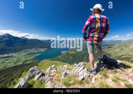Escursionista sulla sommità del Monte Berlinghera guarda verso Colico e il Monte Legnone, provincia di Sondrio, Lombardia, Italia, Europa Foto Stock