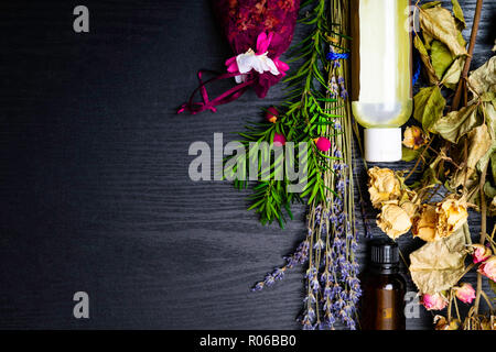 Bottiglie di rose olio essenziale di rosa appassita e petali di fiori di lavanda su sfondo di legno, copia spazio ancora la vita, la salute e la bellezza, spa concept. Asciugare lav Foto Stock