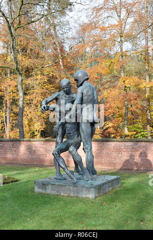 Una statua di bronzo in autunno nel Cimitero di Guerra a Reimsbach raffigura due uomini che trasportano una ferita mortale vittima come simbolo dell'impotenza dell'uomo. Foto Stock