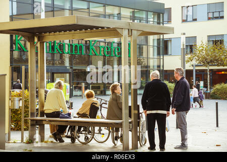 Ottobre 2018. Germania, Helios Klinikum Krefeld. Un gruppo di pensionati in sedie a rotelle poggia su un quadrato in un parco vicino l'entrata dell'ospedale. Foto Stock