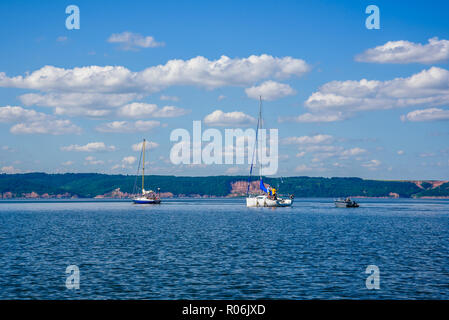 Due barche a vela e barche a motore sul fiume. Foto Stock