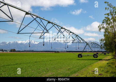 Un perno centrale irrigatore impostato su una fattoria rurale in un grande campo pronto per irrigare le colture in primavera in Nuova Zelanda Foto Stock