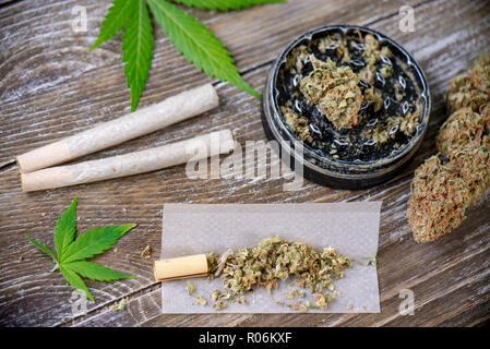 La Cannabis giunti con carta di laminazione e macinare su uno sfondo di legno Foto Stock