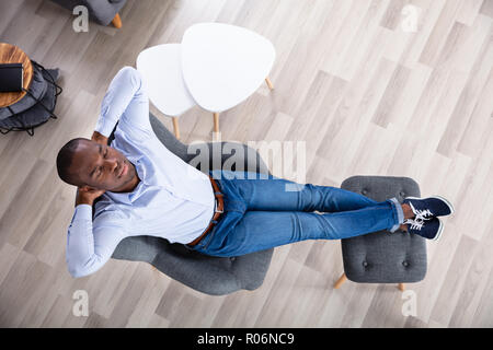 Elevato angolo di visione di un giovane uomo di dormire sulla sedia a casa Foto Stock