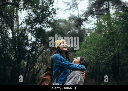 Coppia giovane in una foresta durante la pioggia avendo divertimento. Allegro uomo e donna con grande tempo insieme nella pioggia. Foto Stock
