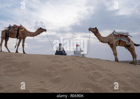 Il Cammello trader rilassante sulla duna di sabbia nel deserto di Thar in Jaisalmer, India. Foto Stock