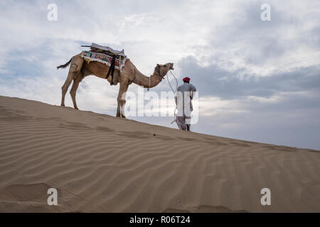 Il Cammello trader rilassante sulla duna di sabbia nel deserto di Thar in Jaisalmer, India. Foto Stock