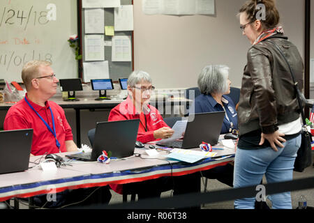 La donna si aspetta di ricevere scrutinio mentre sondaggio intermedia lavoratore (elezione officer) verifica l'identità di elettore durante 2018 elezioni intermedia - Virginia STATI UNITI D'AMERICA Foto Stock