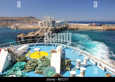 Il traghetto parte da riva a Cirkewwa ferry terminal con onde sul mare blu dell'acqua. Vista dal bordo Foto Stock