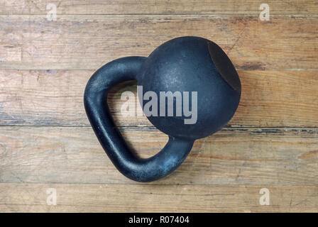 Nero kettlebell pesanti sullo sfondo di legno Foto Stock