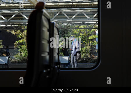 Vista da un treno di un uomo in attesa su una piattaforma del treno Foto Stock