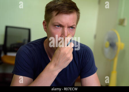 Giovane uomo bello utilizzando l'asma inalatore a casa Foto Stock