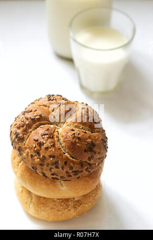 Frumento e segala Kaiser panini con lino e i semi di sesamo servito con latte e sana prima colazione. Foto Stock