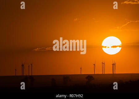 Bel tramonto con turbine eoliche sagome sulla collina. Foto Stock