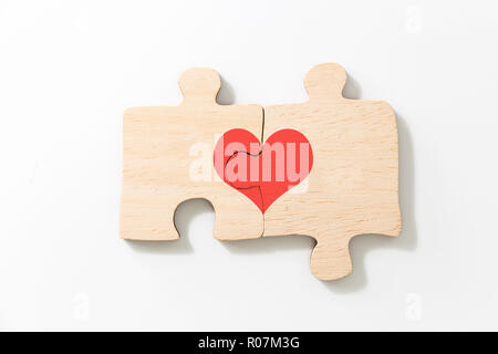 Due sono uniti i pezzi del puzzle in legno, con cuore rosso su sfondo bianco. Foto Stock