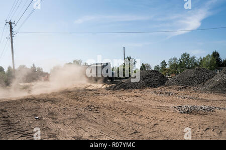 Un carrello con pietre nel rimorchio si muove lungo la via, il prelievo di una polvere. Foto Stock