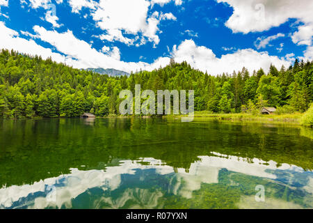 Idilliaco paesaggio estivo con chiaro lago di montagna nelle Alpi. Tranquillo paesaggio naturale delle Alpi, l'Europa. La riflessione di acqua, cielo blu, la pineta Foto Stock