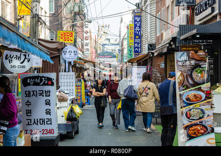 Una vista lungo un vicolo occupato rivestita con bancarelle del mercato coperto, Bupyeong Khangtong Mercato in Busan, Corea del Sud. Foto Stock