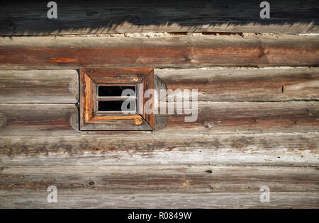 Piccola finestra di legno nella parete di legno vecchio log house. Spazio per il testo. Foto Stock