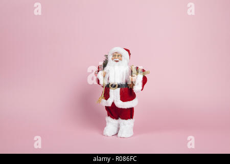 Un babbo natale di peluche di figurine su uno sfondo di colore rosa. Armonia di colori. Il minimo di still life fotografia a colori Foto Stock