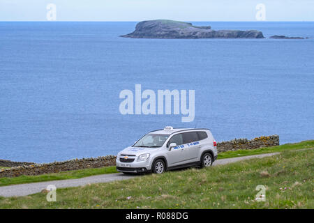 Guida Taxidriver King's taxi con i turisti lungo la desolata strada costiera in Shetland, Scotland, Regno Unito Foto Stock