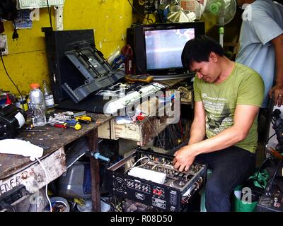 ANTIPOLO City, Filippine - 27 ottobre 2018: un uomo di riparazione risolve un elettronico oggetto domestico presso il suo negozio di riparazione. Foto Stock