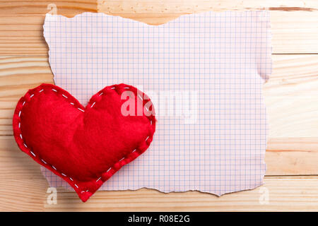 Vuoto strappato il foglio di carta con fatti in casa cuore rosso su un il giorno di San Valentino. Naturale di un tavolo di legno. Copia dello spazio. Foto Stock