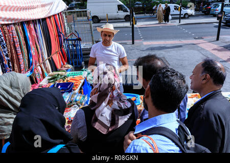 Street scene East London, Whitechapel Market trader che mostra gadget per la preparazione di cibo alle persone, Mile End Road Londra, Inghilterra UK Foto Stock