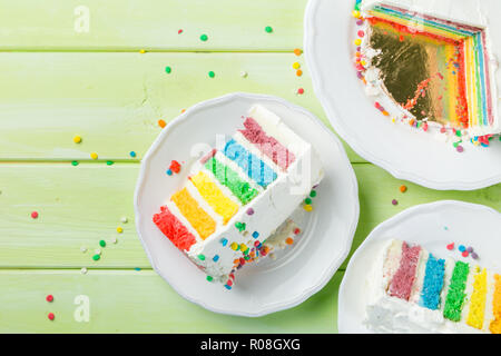 Compleanno di sfondo - Striping torta arcobaleno con glassa bianca decorazioni, spazio di copia Foto Stock