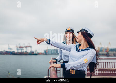 Due college studenti donne di Marine Academy a piedi dal mare indossando uniforme. Amici punta in distanza sul molo. La flotta navale di Ucraina Foto Stock