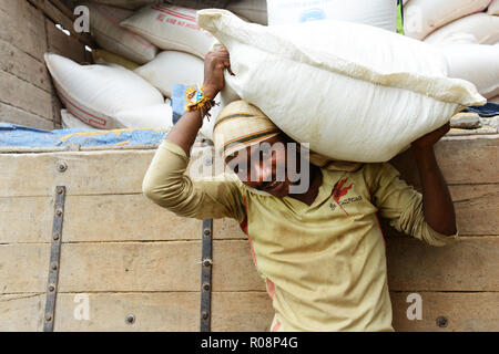 Scaricare grossi sacchi di miglio in un mulino di miglio e di fabbrica in Karnataka, India. Foto Stock