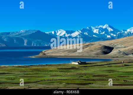 Montagne coperte di neve derivanti dietro le profonde acque blu del Tso Moriri, che si trova a 4.595 m sopra il livello del mare nella zona Changtang. Foto Stock