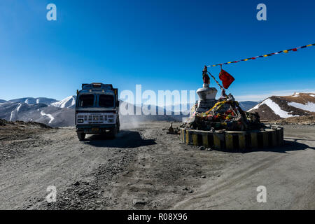 Un carrello passante Taglang La (5.325 m), il massimo passaggio sul Manali-Leh autostrada, Montagne coperte di neve in lontananza. Foto Stock