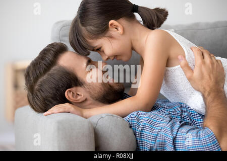 Figlia e padre sorridente giacente insieme sul lettino Foto Stock