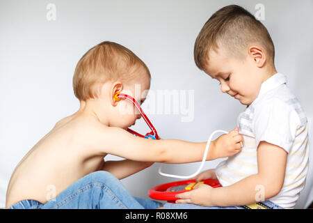 Bambini che giocano il medico e il paziente. Due ragazzini utilizzando uno stetoscopio. Controllare il battito cardiaco. Bambini giocano medico Foto Stock