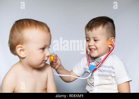 Bambini che giocano il medico e il paziente. Due ragazzini utilizzando uno stetoscopio. Controllare il battito cardiaco. Bambini giocano medico Foto Stock