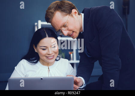 Due giovani uomini di affari che guardando il laptop e discutono dei dati. Business nel concetto di ufficio. Foto Stock