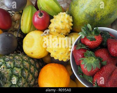 Varie colorata frutta tropicale, selezione nel vassoio in legno su, vista dall'alto, ananas e fragola, dragon di frutta, arancio, limone, papaia, star fruit,vegan Foto Stock