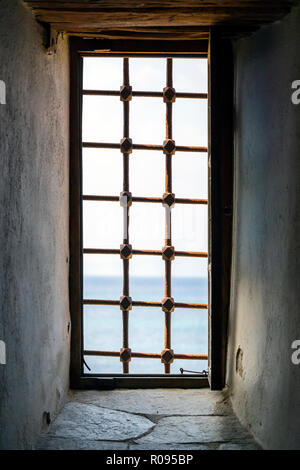 Vecchia finestra con barre di metallo in un antico edificio di pietra Foto Stock