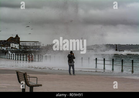 Penzance, Cornwall, Regno Unito. Il 3 novembre 2018. Regno Unito Meteo. Come Oscar tempesta si avvicina al Regno Unito e grandi onde hit Penzance fronte mare questo giovane erano di fronte al mare a fotografare le onde. Credito: Simon Maycock/Alamy Live News Foto Stock