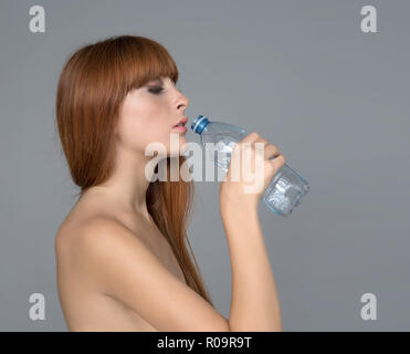 Varie espressione da ragazza giovane con una bottiglia d'acqua su sfondo neutro Foto Stock