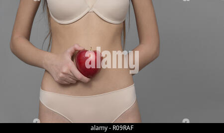 Varie espressione da ragazza giovane con apple frutta fresca su sfondo neutro Foto Stock