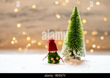 Sybolic paesaggio con natura concettuale, un unico verde albero di Natale in piedi nella neve su uno sfondo di luci bianche Foto Stock