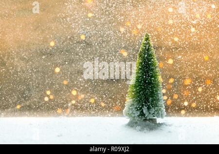 Sybolic paesaggio con natura concettuale, un unico verde albero di Natale in piedi nella neve su uno sfondo di luci bianche Foto Stock