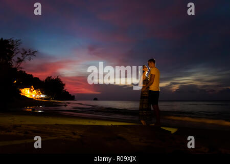 Tramonto paesaggio con coppia giovane sulla tropicale Isola di Tioman in Malesia. Bella notte seascape dell Asia del sud-est sulla spiaggia Tekek. Foto Stock