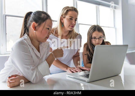 Un bambino con la tecnologia tablet e computer laptop in insegnante di classe sullo sfondo Foto Stock