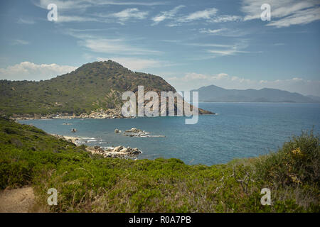 Insenatura naturale tra le montagne e il mare nel sud della Sardegna con il contorno di una vegetazione tipica della macchia mediterranea che cresce spontanea Foto Stock