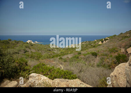 Paesaggio con rocce e vegetazione tipica del Mediterraneo e sullo sfondo il mare all'orizzonte. Foto Stock